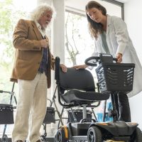 Staff showing electric scooter to senior man